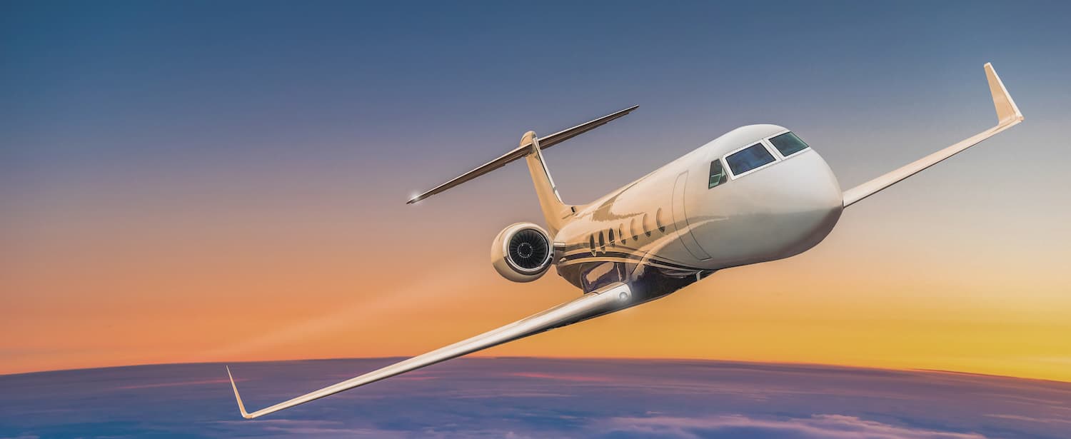 Private jet flying above dramatic clouds at sunset